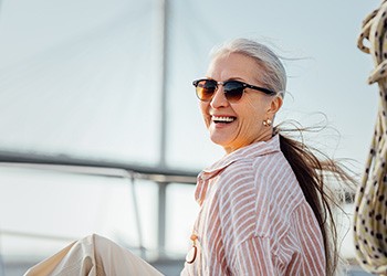 Woman with sunglasses smiling while sitting on boat
