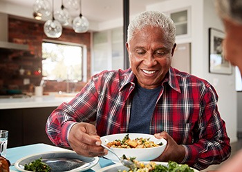 Senior man filling plate at table