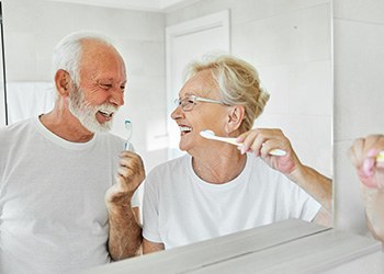 Senior couple smiling while brushing their teeth