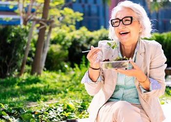 Lady smiles while eating salad