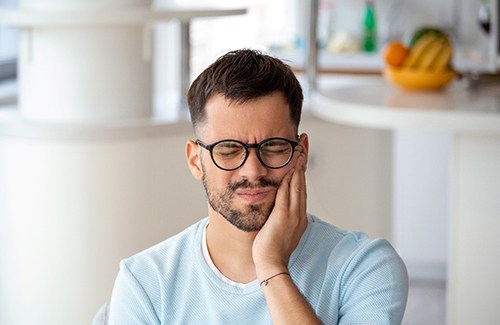 Man with black glasses experiencing toothache
